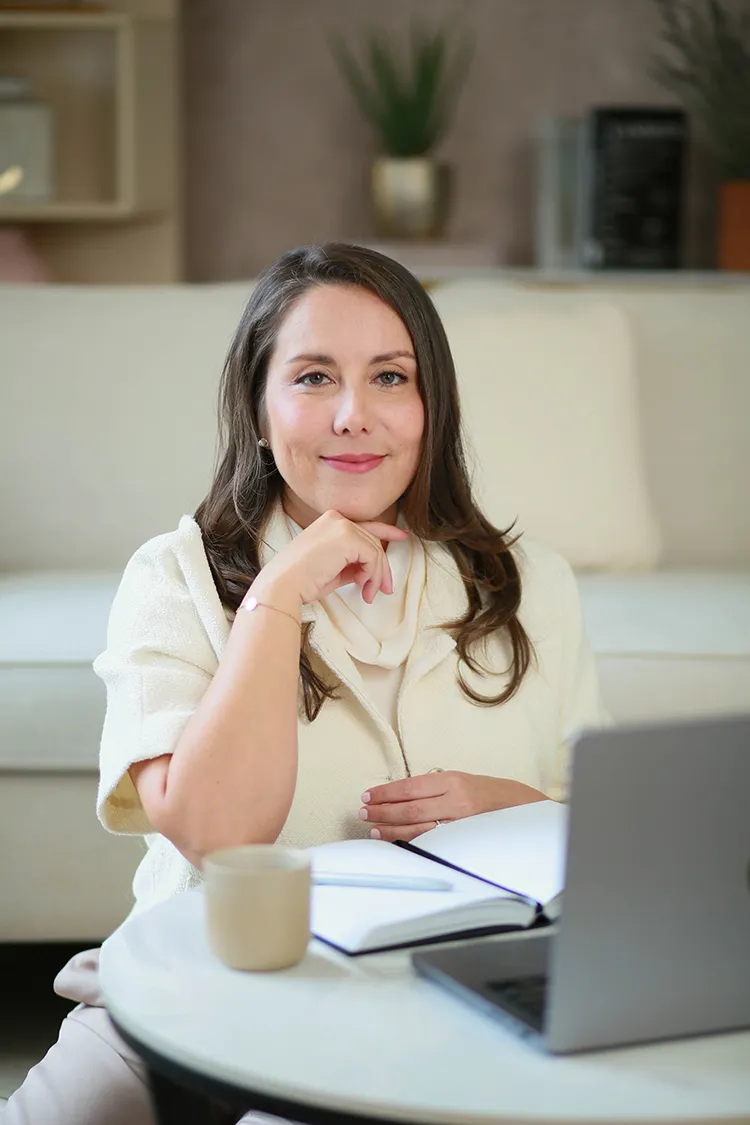 Carla Escot at a table with her laptop and notebook, listening